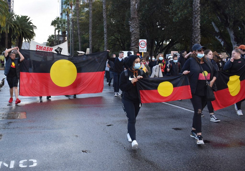 Protestors holding Aboriginal flags while they march